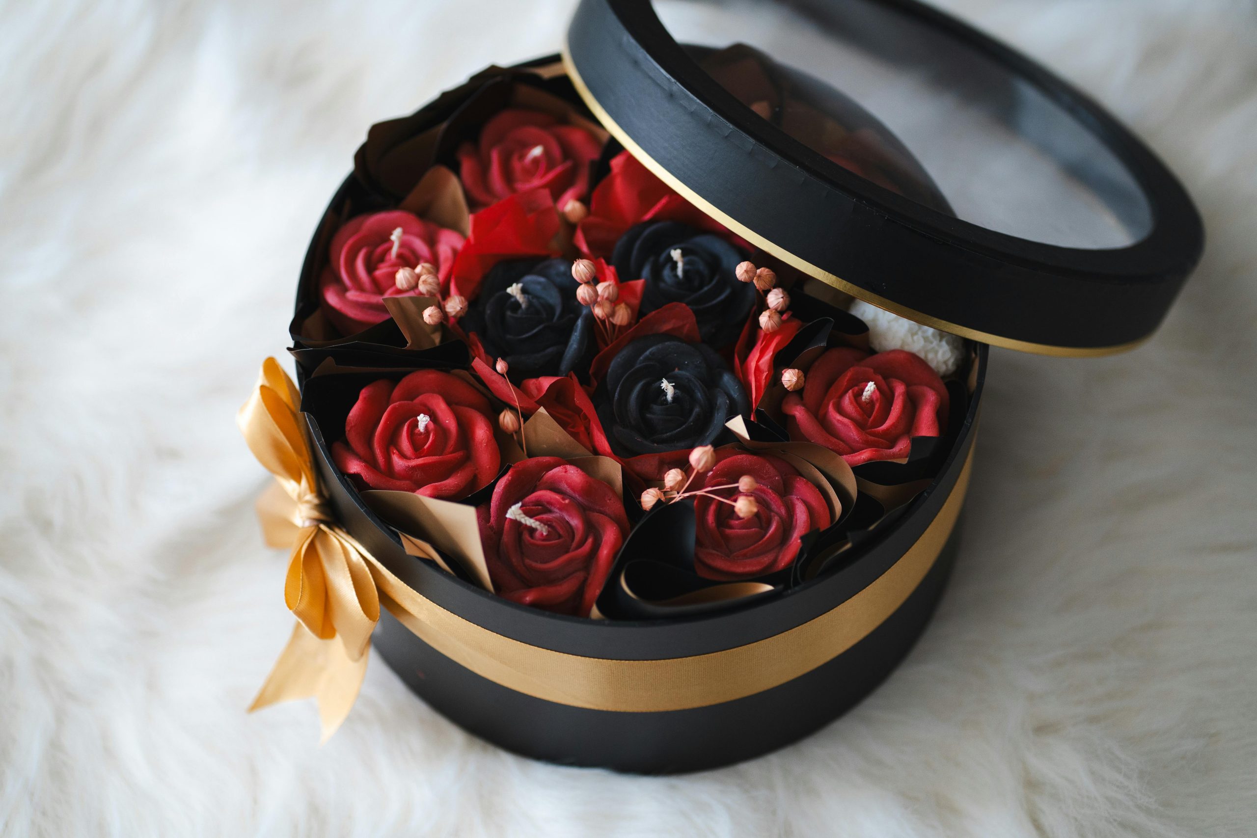 Luxurious round gift box featuring vibrant red and black artificial roses, perfect for special occasions.